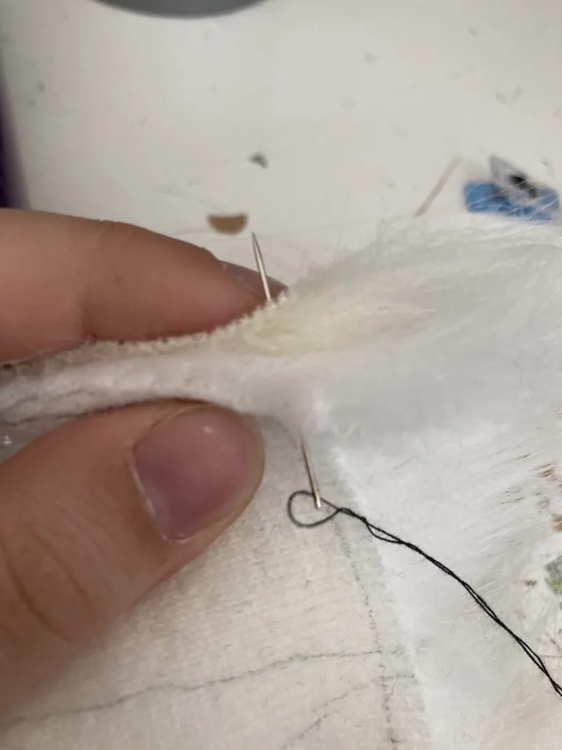 Needle sitting halfway through two sandwiched pieces of faux fur