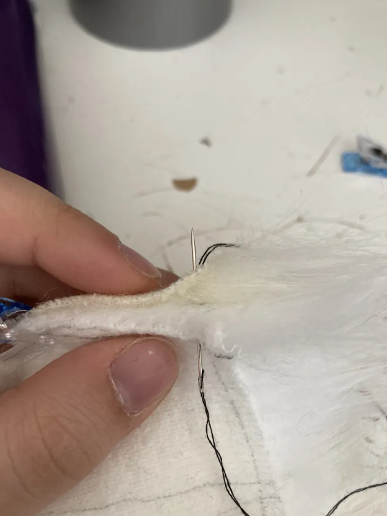 Needle again sitting halfway through two sandwiched pieces of faux fur