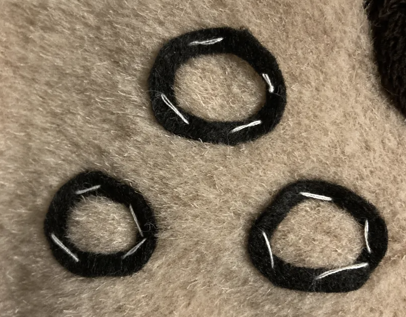 Three muzzle dots basted into place onto a muzzle with white thread