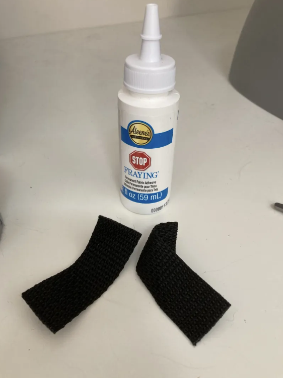 Bottle of fray adhesive and two strips of nylon webbing