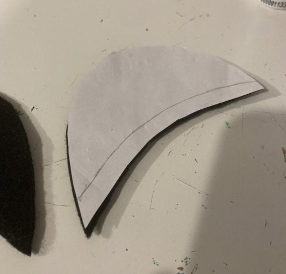 Same paper template resting on top of the eyelid base, this time with a line drawn towards the bottom